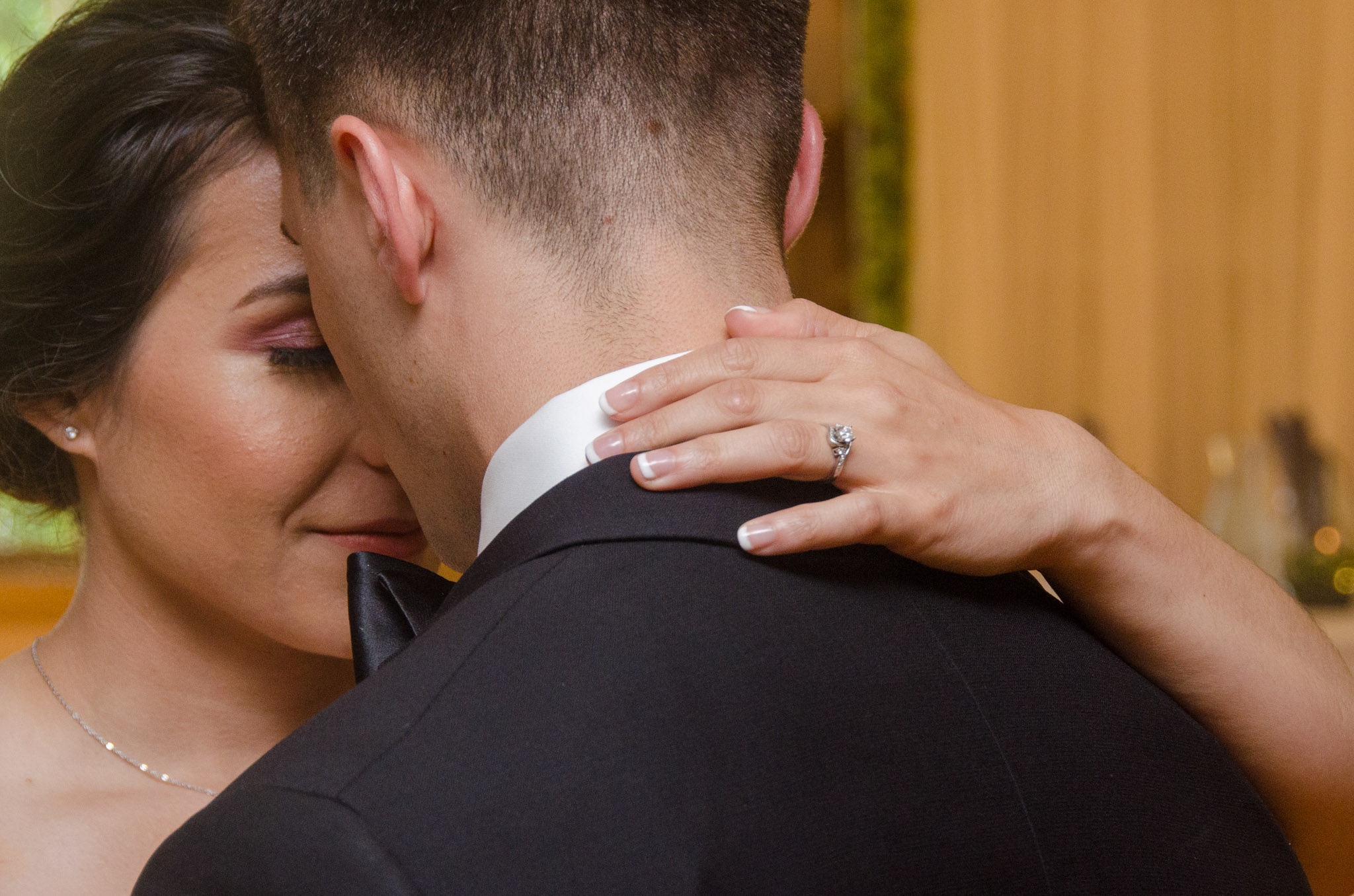 Bride embracing the groom with her wedding ring visible on his shoulder