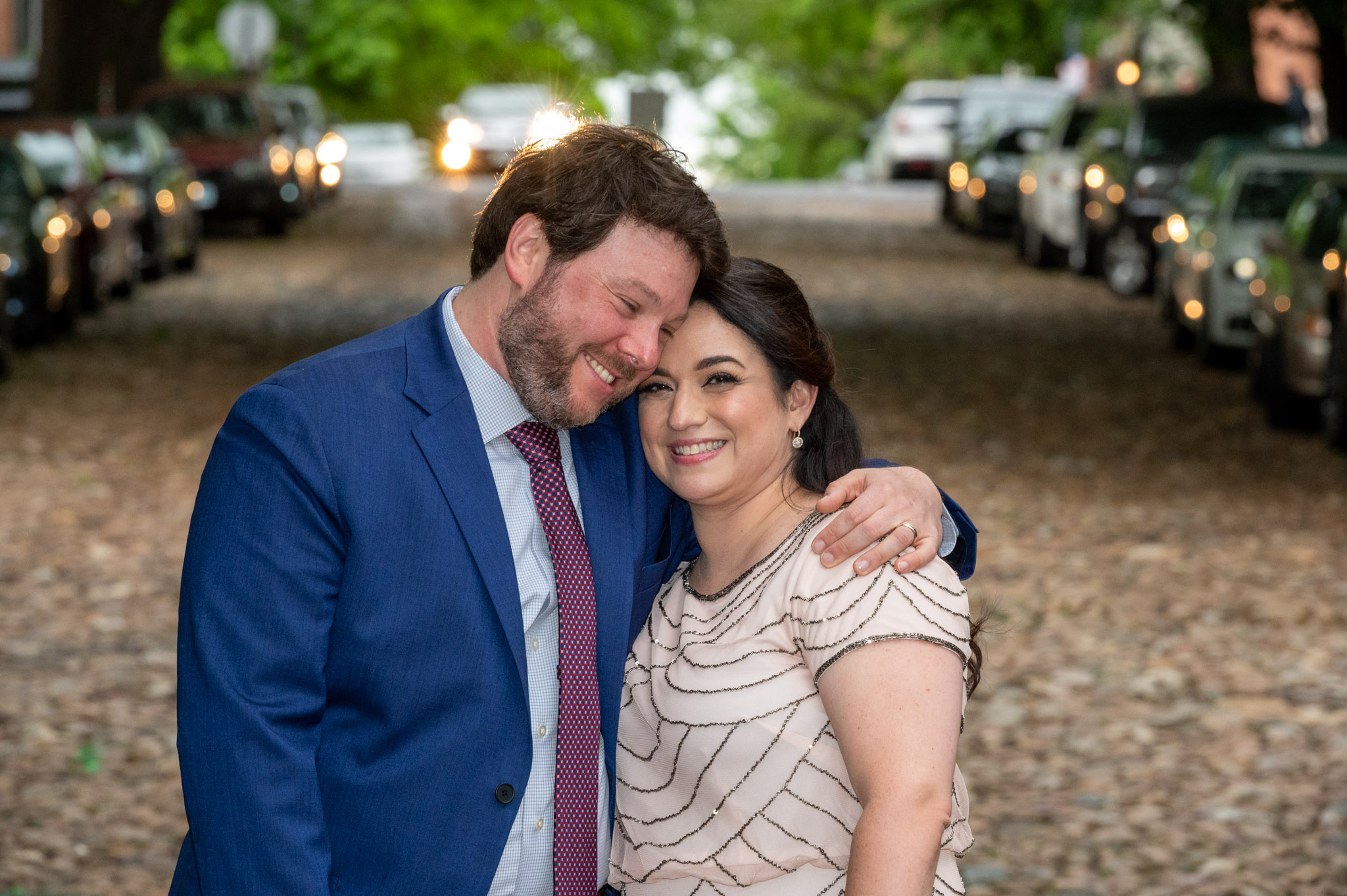 Couple leaning together on a tree-lined street